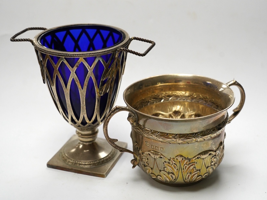 An Edwardian repousse silver porringer, Daniel & John Welby, London, 1905, height 73mm, together with a late Victorian silver two handled sugar vase with blue glass liner, London, 1895. Condition - fair